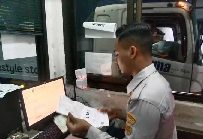 CEK: Petugas di UPPKB Sedarum BPTD XI wilayah XI Provinsi Jawa Timur memeriksa kelengkapan surat kendaraan yang masuk ke jembatan timbang. (Foto: Istimewa)