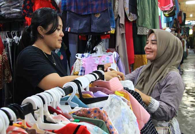 TRANSAKSI : Norma (kiri) melayani salah seorang calon pembeli di kios pakaiannya di Pasar Semampir, Kecamatan Kraksaan. (Foto: Agus Faiz Musleh/Jawa Pos Radar Bromo)