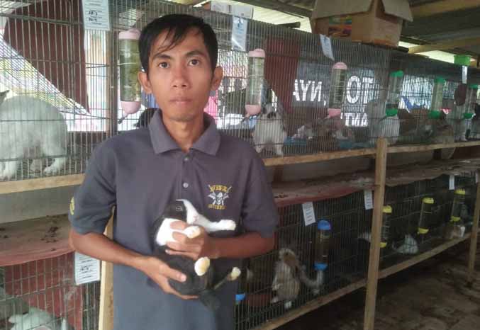 SAYANG KELINCI: Abdur Rohim Syarifuddin, menggendong salah satu kelinci peliharaannya. Kini, ia memiliki puluhan kelinci yang dibudi daya di rumhanya. (Foto: Istimewa)