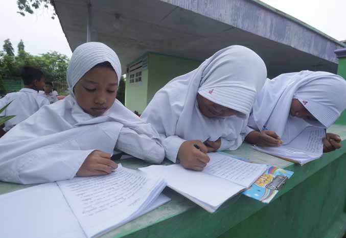 HANYA SEBENTAR: Siswi SDN Kalirejo 2 saat belajar di teras rumah warga. (Foto: Zainal Arifin/Jawa Pos Radar Bromo)