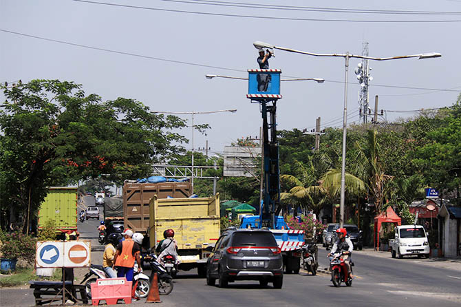 BAKAL BERTAMBAH: Sejumlah pekerja tengah membenahi PJU di Raci, Bangil, yang alami kerusakan beberapa waktu lalu. Tahun ini bakal ada tambahan 538 PJU baru yang disebar di 21 kecamatan wilayah Kabupaten Pasuruan. (Mokhamad Zubaidillah/Radar Bromo)