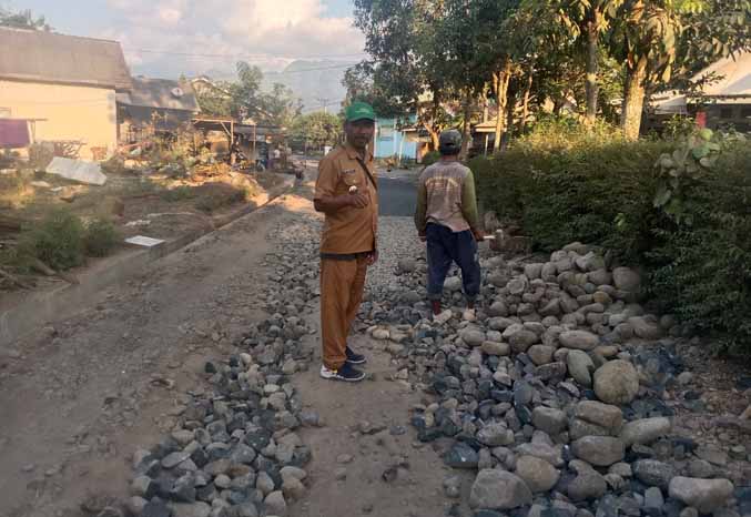 PROGRES SAAT INI: Kepala Desa Bucor Kulon Abd Sukur saat berada di lokasi jalan aspal yang masih tahap pengerjaan. (Foto: Agus Faiz Musleh for Jawa Pos Radar Bromo)
