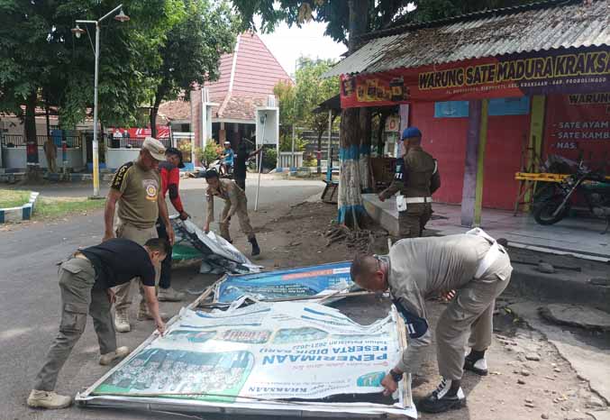 SERING: Personel Satpol PP menurunkan banner yang dipasang di pohon perindangan. (Foto: dok Jawa Pos Radar Bromo)