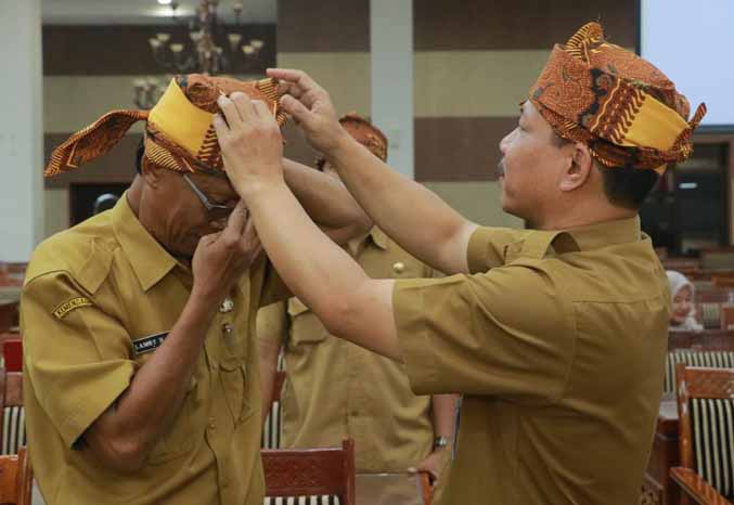 LESTARIKAN BUDAYA: Kepala Diskominfo Kabupaten Probolinggo Yulius Christian memasangkan udeng kepada salah satu anak buahnya. (Foto: Diskominfo Pemkab Probolinggo for Jawa Pos Radar Bromo)