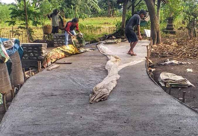 LEBIH BAIK: Sejumlah pekerja merabat beton jalan di RT 9/RW 5, Dusun Gumukbang, Desa Gading Kulon. (Foto: Achmad Arianto/Jawa Pos Radar Bromo)
