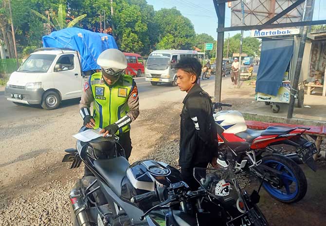 MENGGANGGU: Anggota Satlantas Polres Probolinggo, menindak pemotor yang mengunakan motor berknalpot brong.