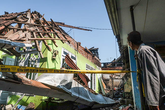 DI-POLICE LINE: Warga mengamati rumah yang ludes dilalap api di Trajeng, Panggungrejo, Kota Pasuruan. (Mokhamad Zubaidillah/Radar Bromo)