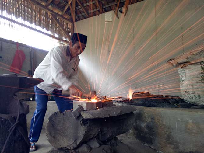 TRADISIONAL: Muhammad Jufri, 57, generasi kelima pembuatan pusaka Penganti. Penempaan besi untuk membuat pusaka masih dilakukan secara tradisional. (Foto: Mukhamad Rosyidi/Jawa Pos Radar Bromo)
