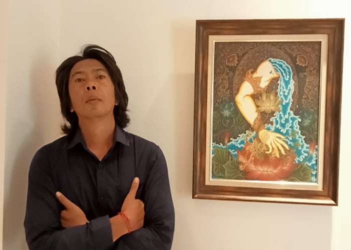 KARYA : Komang Sudiarta, 40, bersama karya lukisannya. (