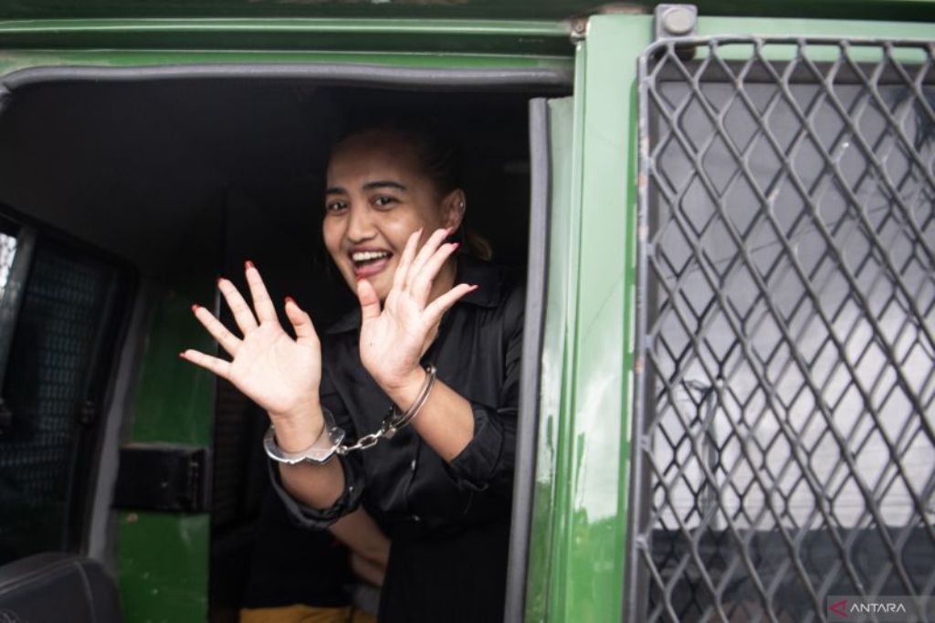 PEMBUAT KONTEN MAKAN BABI: Lina Mukherjee melambaikan tangan kepada awak media saat kasusnya dilimpahkan tahap II ke Kejari Palembang.