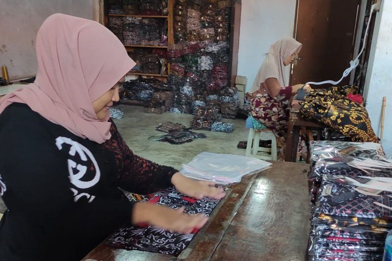 Dua karyawan Batik Ruzza sedang menyiapkan produk untuk dijual di Shopee