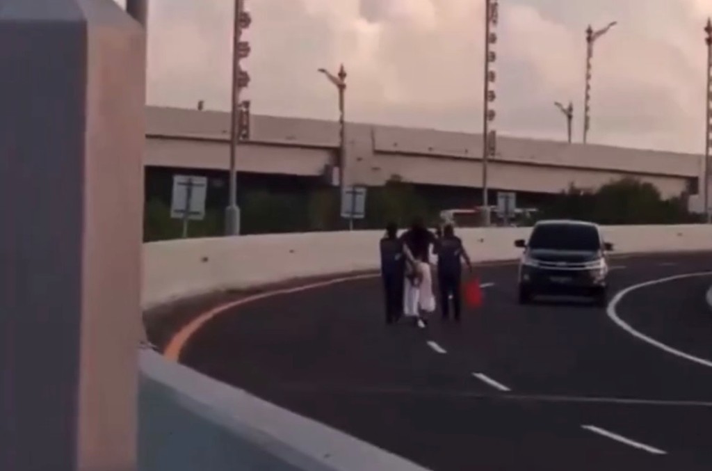 DIKAWAL: Dua petugas JBT mengawal WNA yang nekat berjalan kaki di Jalan Tol Bali Mandara, Sabtu (15/7).