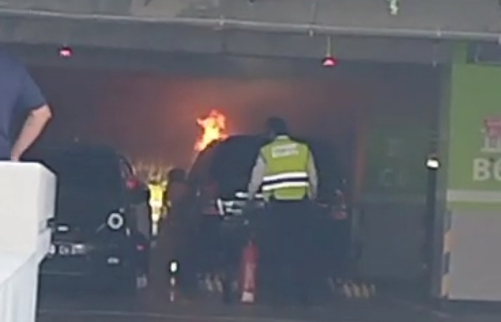 TERBAKAR: Tangkapan layar mobil Toyota Inova warna hitam berplat DK 1227 FBE terbakar di parkir tingkat Bandara Ngurah Rai Bali.