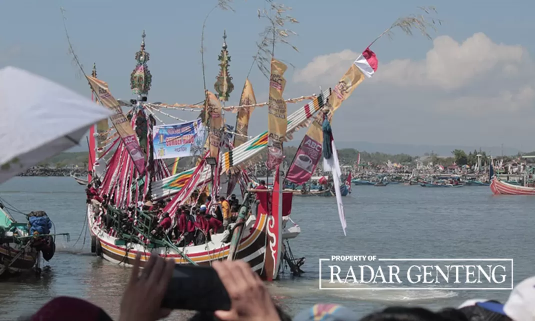 Sesaji petik laut yang telah didoakan tokoh nelayan Muncar, Banyuwangi dilarung ke laut menggunakan kapal kecil diikuti warga setempat.