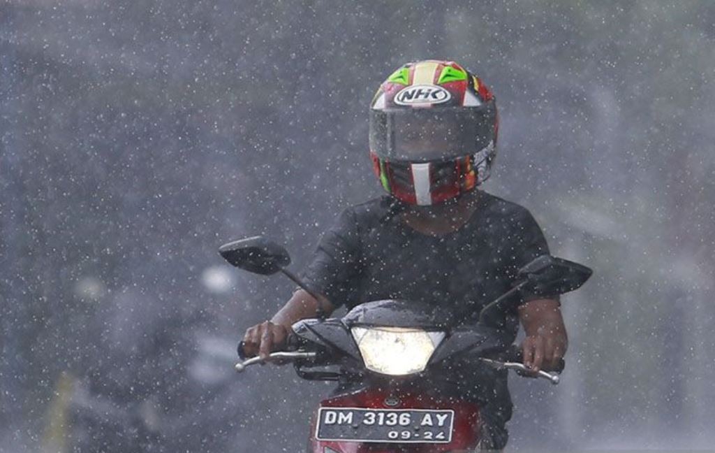 Seorang pengendara motor melaju di tengah hujan di Kota Gorontalo.