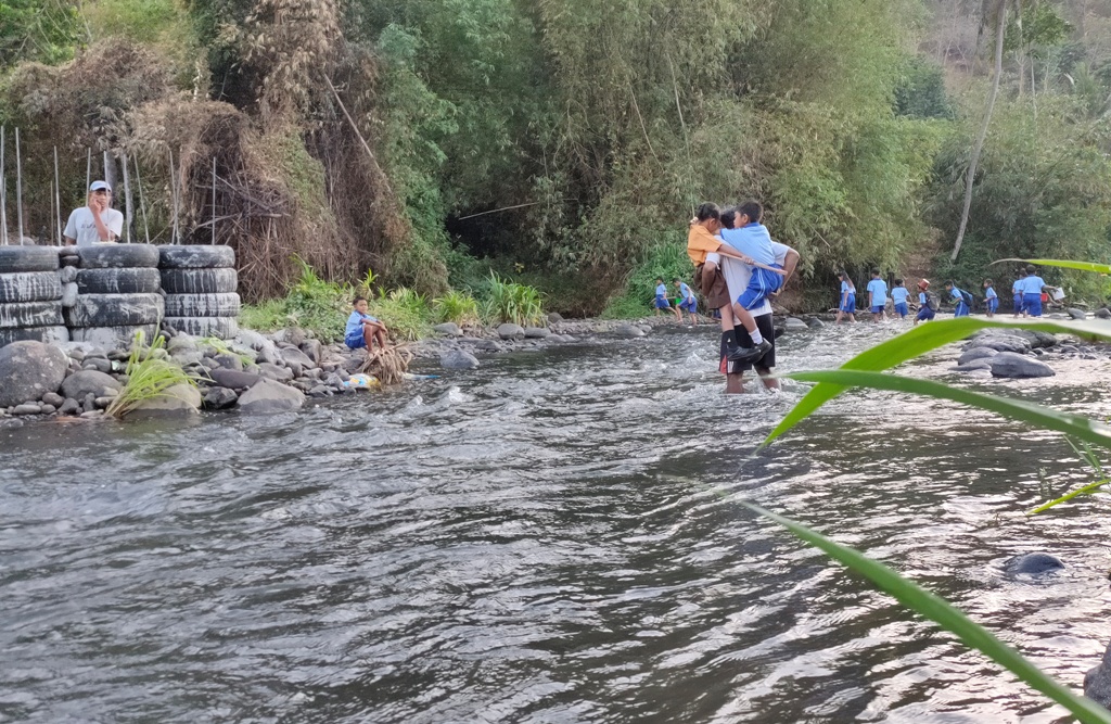 Siswa dari wilayah Desa Lokapaksa dan Desa Ularan, Buleleng, Bali, menyeberang sungai menuju sekolah.
