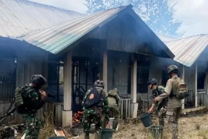Anggota TNI/Polri memadamkan rumah petugas kesehatan yang dibakar KKB sebelum kontak tembak di Ilaga, Papua Tengah.