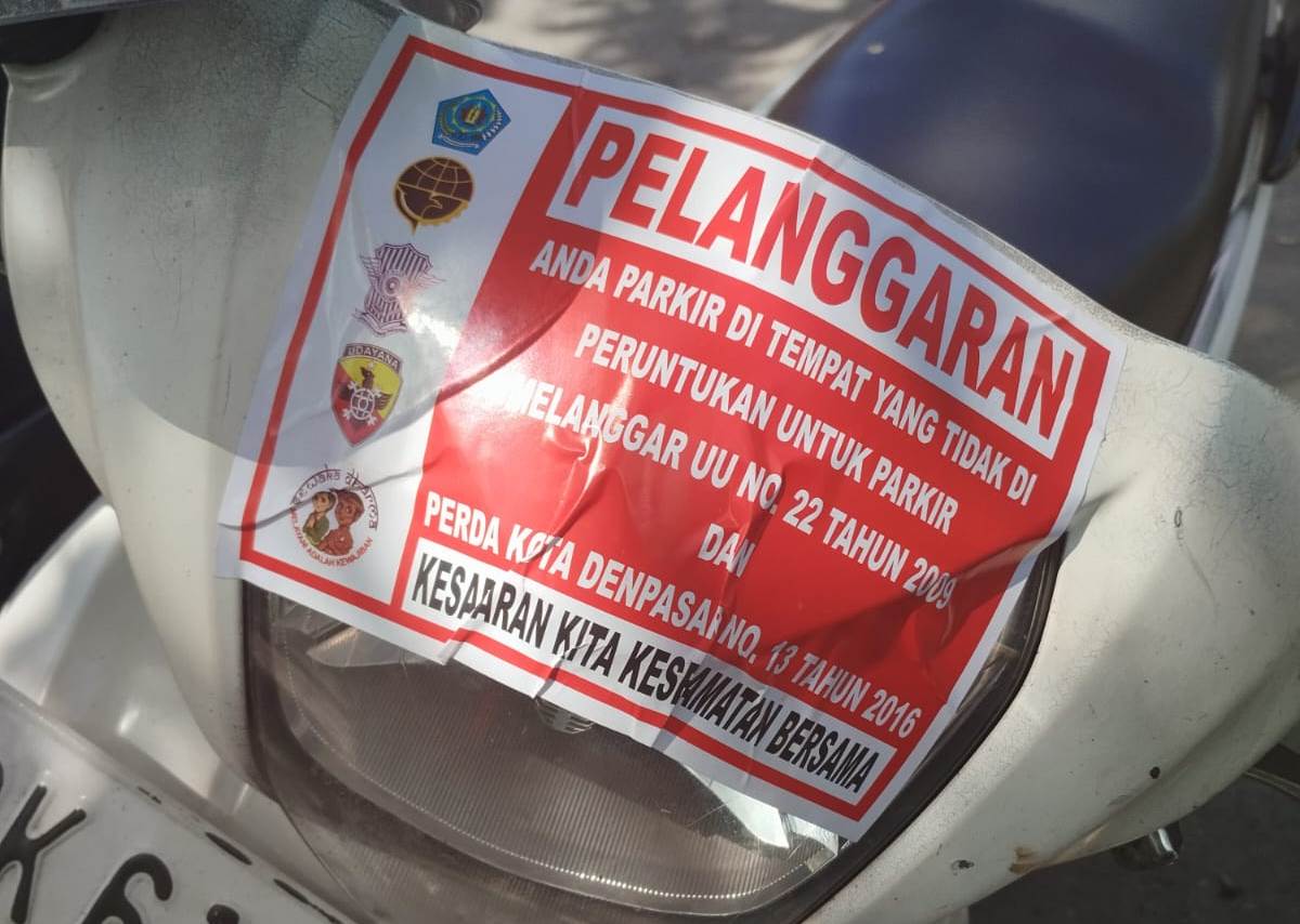 TEGURAN: Petugas gabungan yang dipimpin Wakasatlantas Polresta Denpasar AKP Aan Saputra menempeli stiker pada kendaraan yang parkir sembarangan.