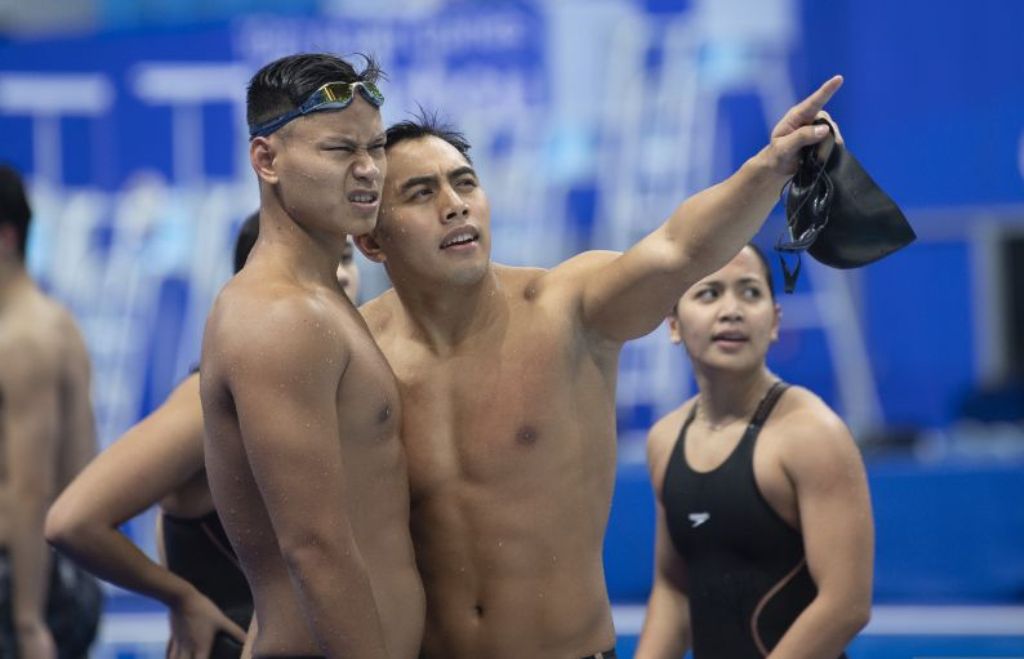 Perenang putra Indonesia Muhammad Dwiky Raharjo (kedua kiri) bersama Joe Aditya Wijaya Kurniawan (kiri) mengamati papan waktu usai final 4x100 meter gaya ganti estafet campuran Asian Games 2022, Rabu