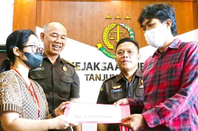 Istri terpidana menyerahkan uang restitusi pada korban penganiayaan di Kejaksaan Negeri Tanjung Perak, Surabaya, Jawa Timur.