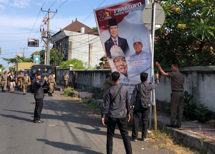 DITERTIBKAN : Anggota Satpol PP bersama tim dari Bawaslu, KPU, kepolisian dan TNI menurunkan baliho parpol dan caleg di perempatan Jalan By Pass Watu Klotok, Senin (13/11).