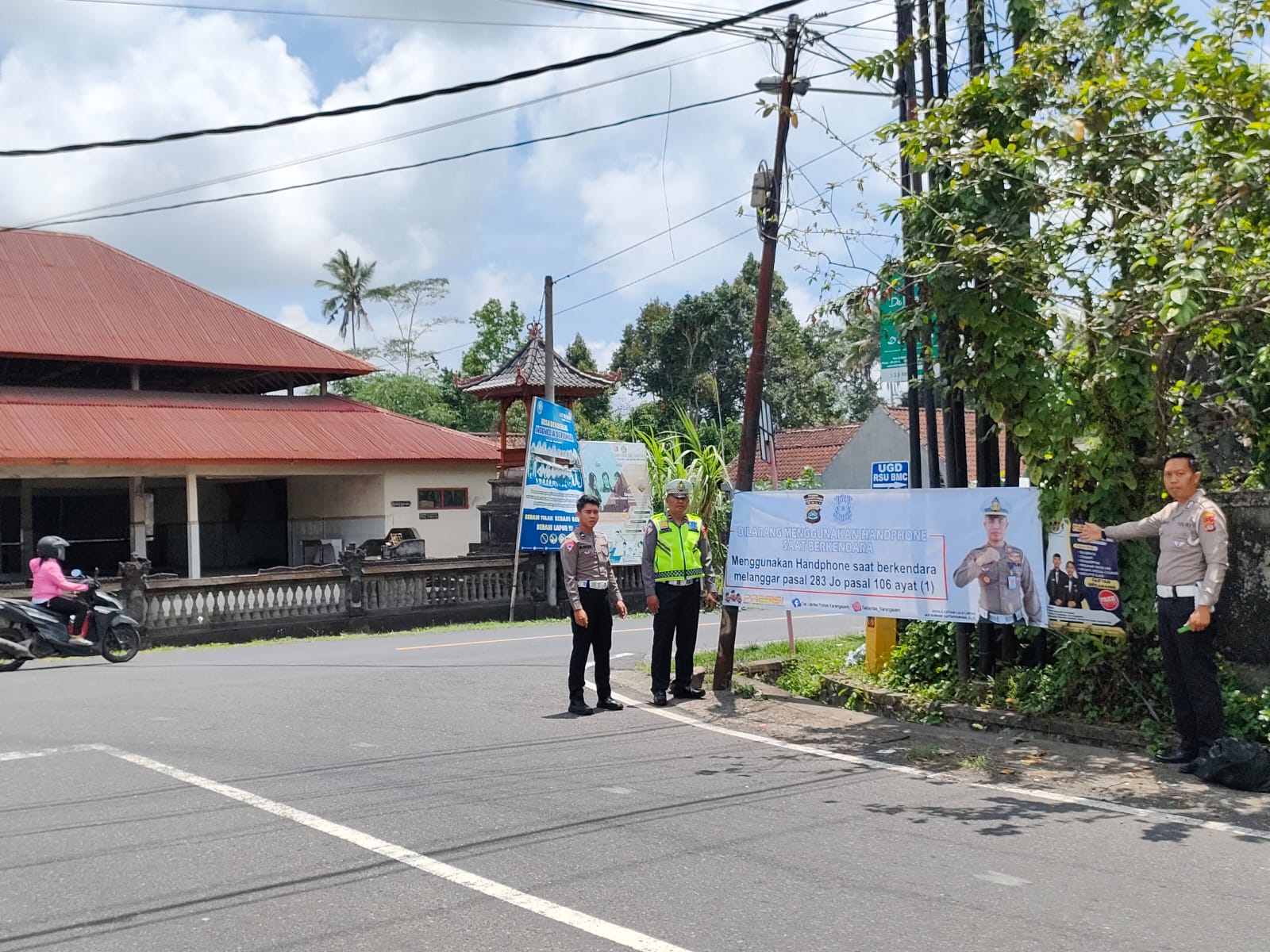 UPAYA: Lantaran kasus lakalantas terus meningkat,  personil Satlantas Polres Karangasem memasang spanduk imbauan kepada pengendara supaya berhati-hati.