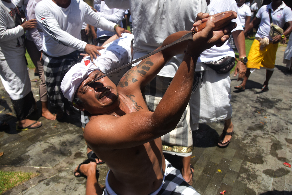 Warga mengalami Kerauhan  menusukan keris ke bagian tubuh saat Upacara Nangluk Merana Desa Adat Kuta, Minggu (10/12)
