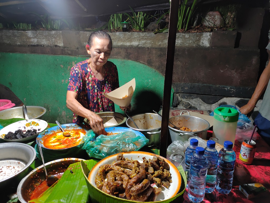 KULINER MALAM DI BULELENG BALI: Mek Wanten sedang melayani pembeli yang membeli nasi campur babi di gerainya.