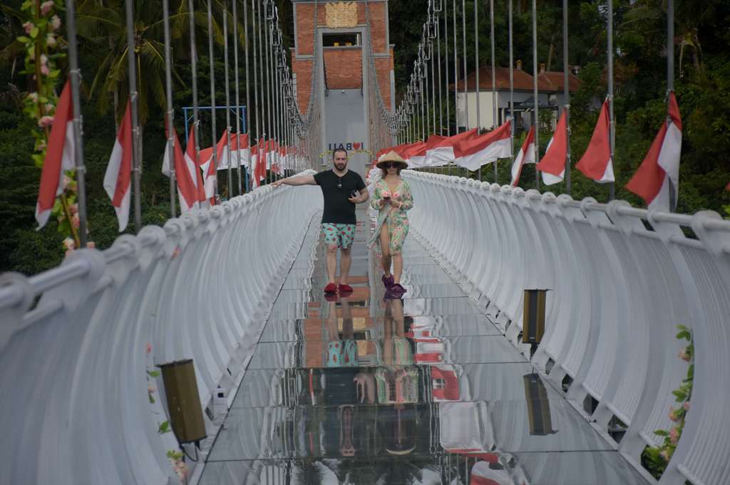 Wisatawan melintas sambil berfoto di Jembatan Kaca  penghubung antara Banjar Tegenungan Desa Kemenuh, Sukawati dengan Banjar Blangsinga Desa Saba, Blahbatuh, Gianyar, Bali, Rabu (17/1).