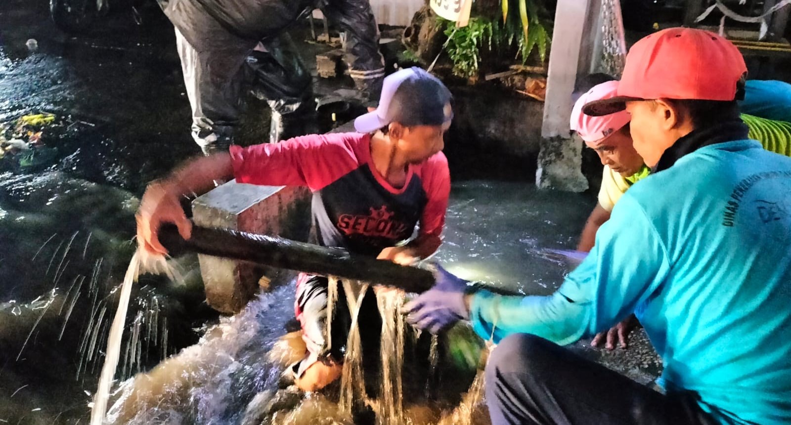 Tim Pasgap Biru Dinas PUPR Kota Denpasar saat membersikan gorong-gorong untuk mengatasi banjir di beberapa ruas jalan Kota Denpasar, Sabtu, 27 Januari 2024.