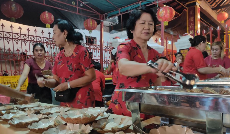 Cindra Dewi sedang menyiapkan makanan untuk dibagikan kepada umat yang datang ke Kelenteng Ling Gwan Kiong, Singaraja, Bali, Sabtu, 10 Februari 2024.