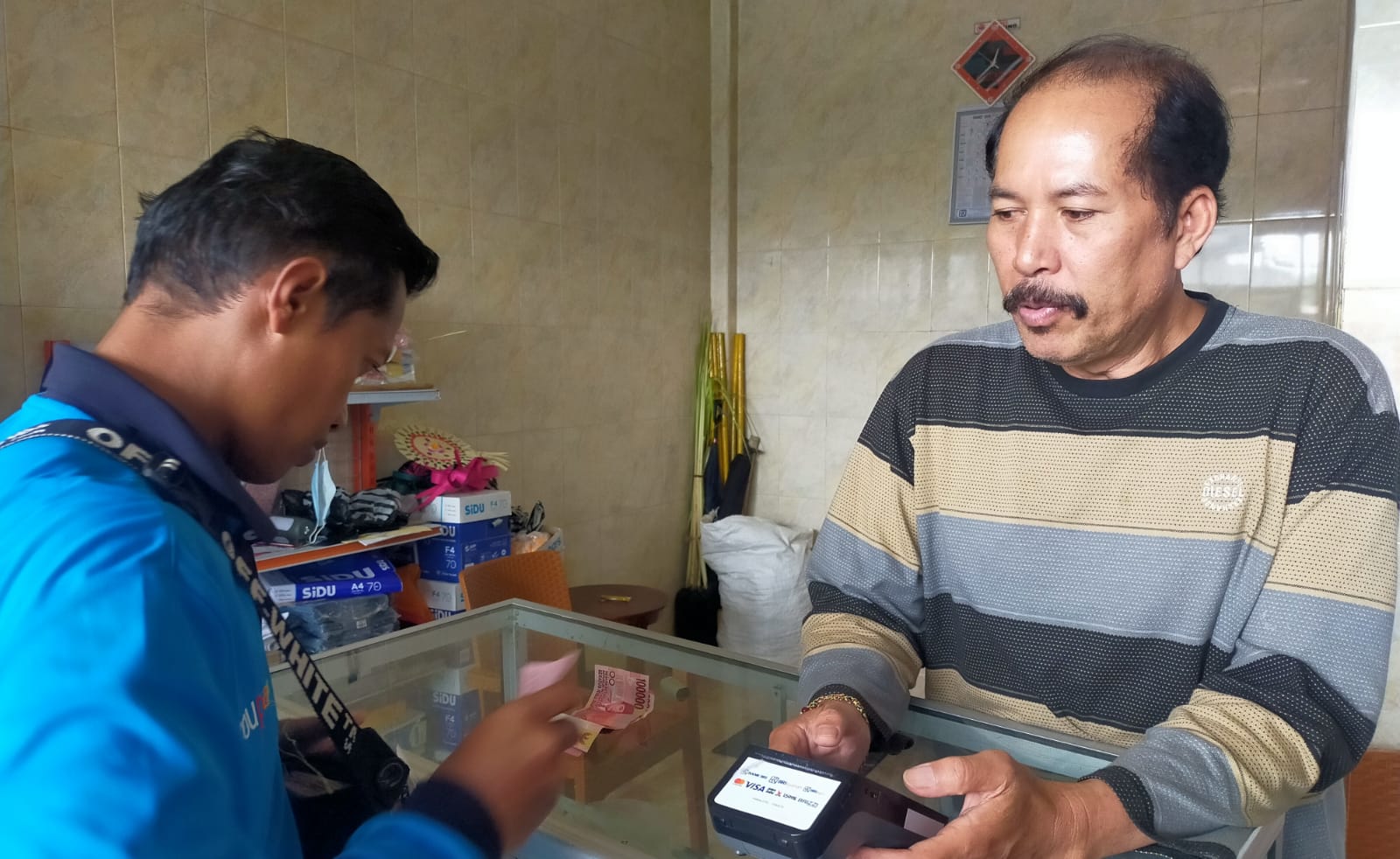 I Gusti Ketut Anom (kanan), Agen BRILink di Desa Kintamani, Kecamatan Kintamani, Kabupaten Bangli, Bali saat melayani nasabah, Minggu, 10 Maret 2024.