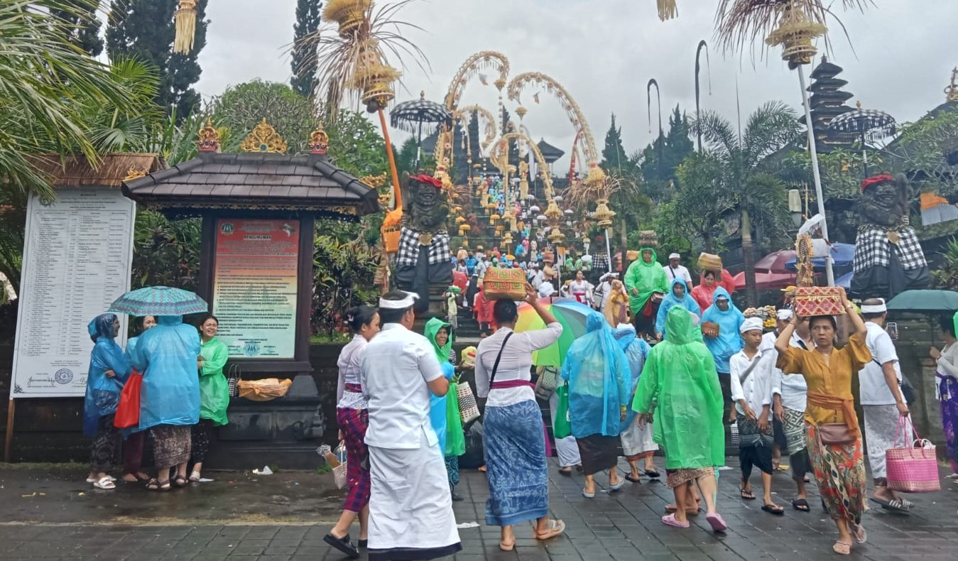 Sejumlah pamedek menggunakan jas hujan saat nangkil ke Pura Agung Besakih, Kecamatan Rendang, Karangasem, Bali, Kamis, 28 Maret 2024.