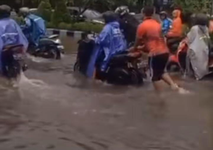 Warga tolong menolong mendorong kendaraan yang mati dan terjebak banjir