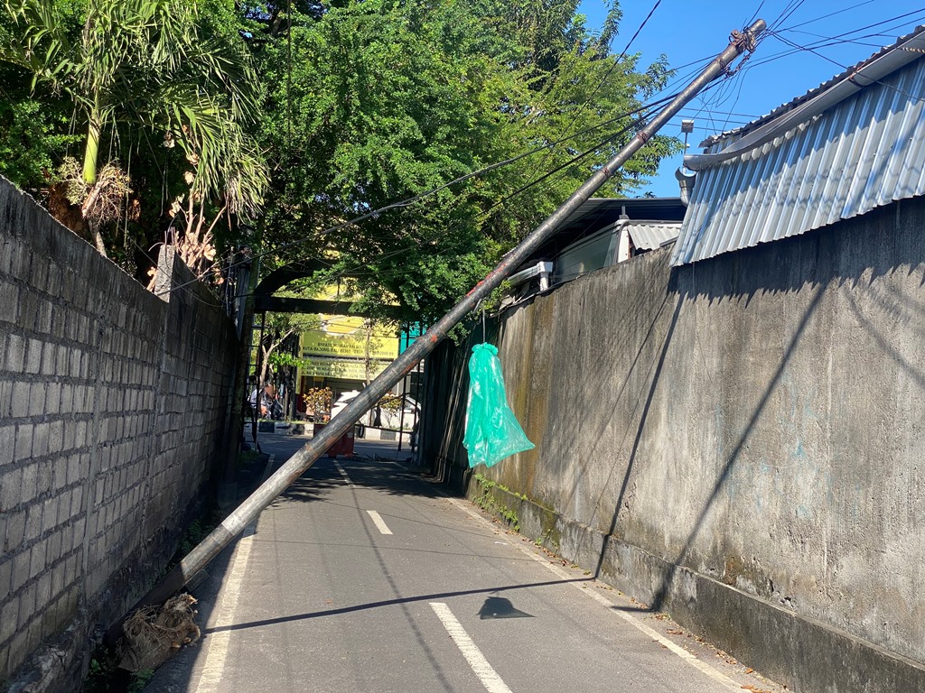 MIRING: Kondisi salah satu tiang provider di Jalan Bhayangkara, Kuta, Badung, Bali yang membahayakan pengguna jalan, Minggu (14/4).