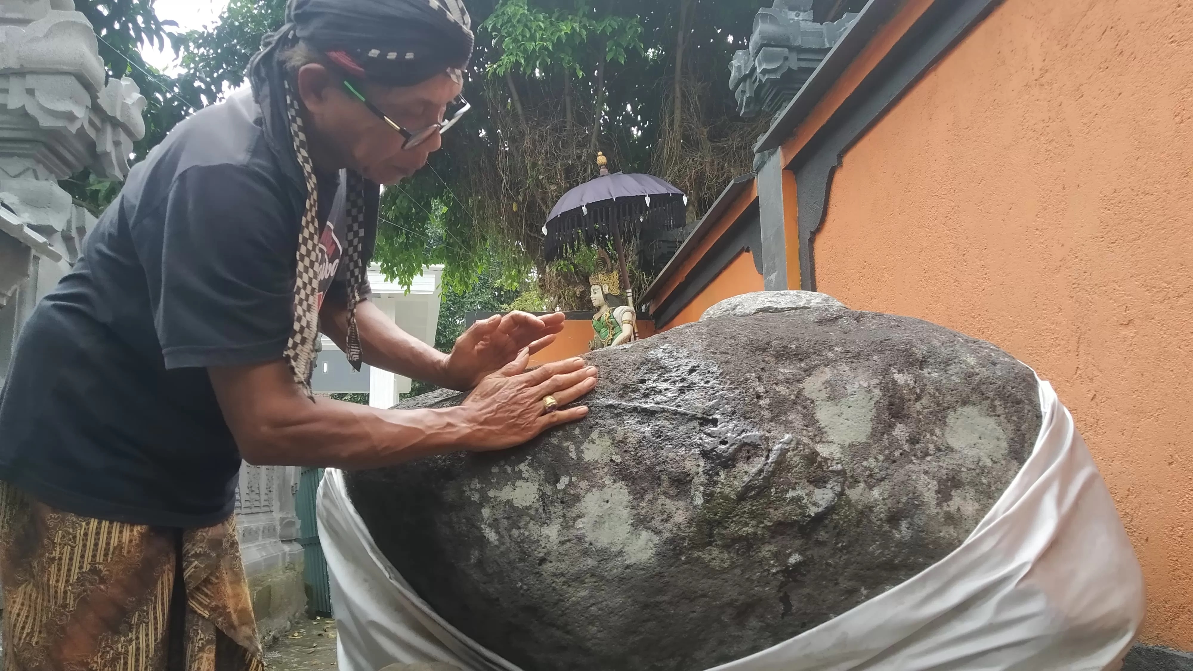 LEBIH JELAS: Tejo Dwi Saputro menunjukkan aksara pada batu di Pura Ngesti Dharma, Dusun Sumberejo, Desa Jambewangi, Kecamatan Sempu, Jumat (12/4). (Gareta Wardani/Radar Genteng)