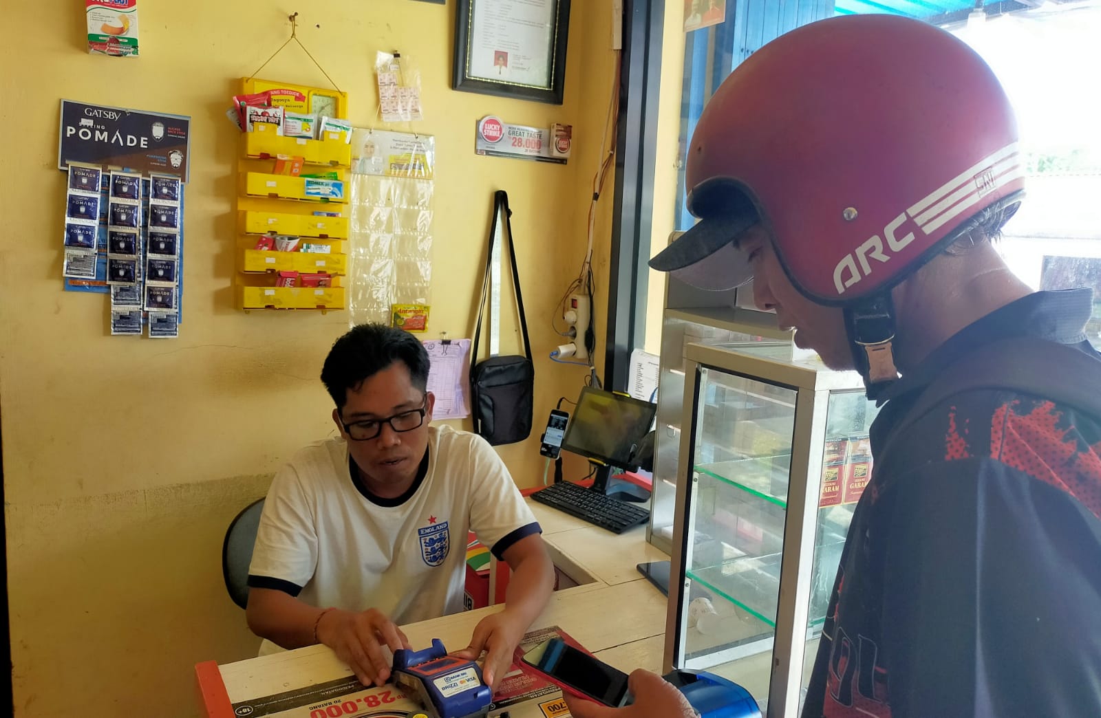 Agen BRILink di Kelurahan Kubu, Kabupaten Bangli, Bali I Putu Alit Arta Yasa (kiri) melayani transaksi perbankan, Sabtu, 13 April 2024.