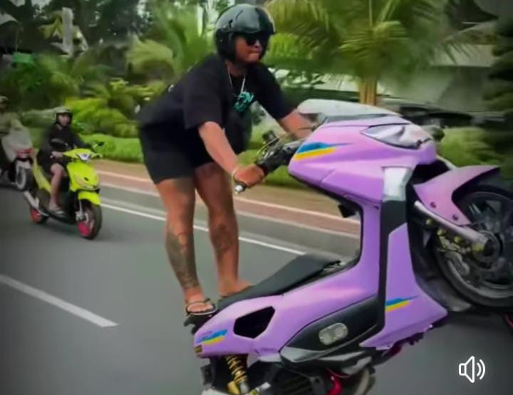 Seorang pemuda melakukan aksi freestyle motor di jalanan umum