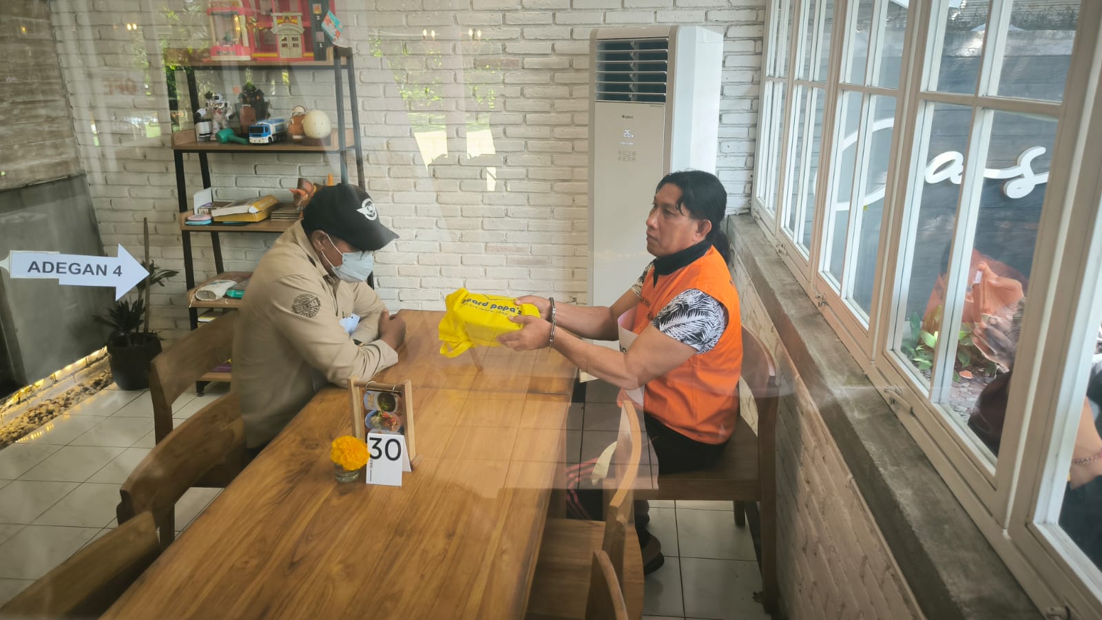 Reka ulang pengusaha AN (pakai topi) menyerahkan amplop dalam tas warna kuning yang isinya uang Rp 100 juta kepada Bendesa Adat Berawa Ketut Riana.