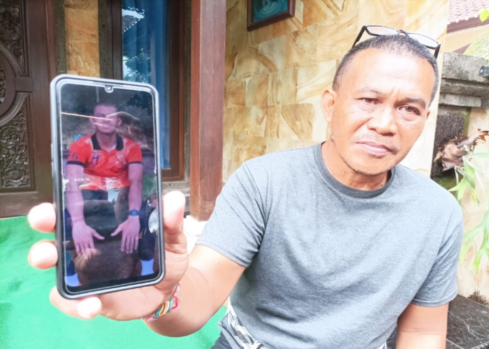 TERPUKUL : I Ketut Suastika menunjukkan foto putranya Putu Satria Ananta Rustika, 19.
