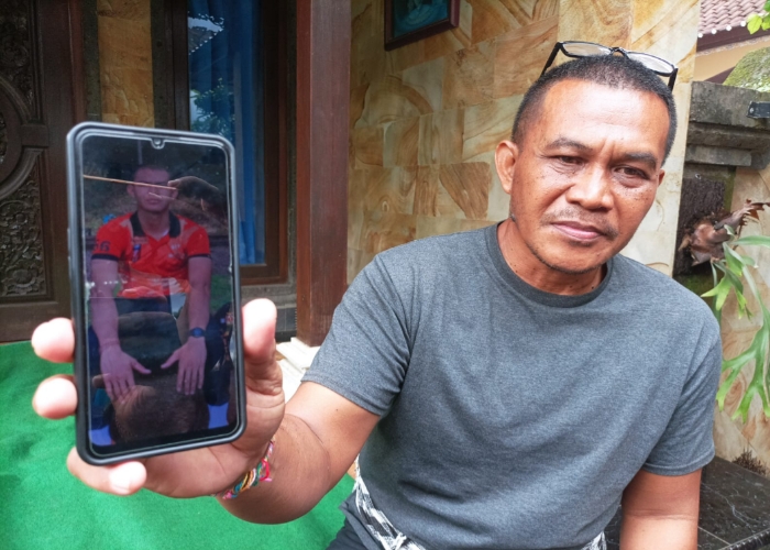 TERPUKUL : I Ketut Suastika menunjukkan foto putranya Putu Satria Ananta Rustika, 19.