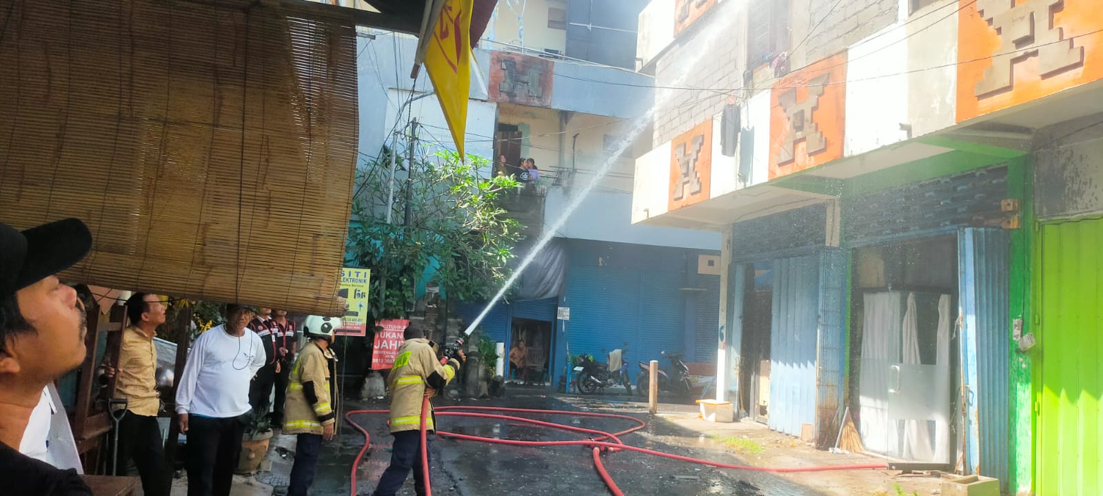 TERBAKAR: Petugas Damkar berusaha memadamkan api di ruko lantai 3 di Kuta yang terbakar. Seorang wanita pingsan usai minta tolong.