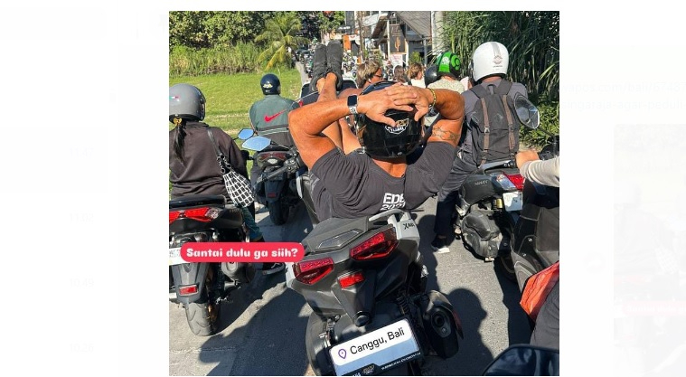 Seorang bule terlihat tiduran di atas motor karena bosan terjebak macet di shortcut Canggu