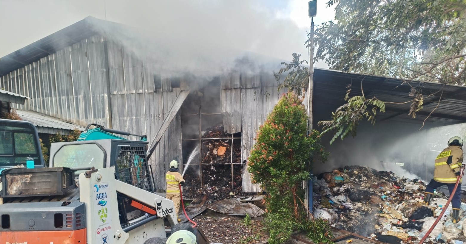 Petugas pemadam kebakaran Kabupaten Badung menyemprot api yang berkobar di gudang TPST Samtaku Jimbaran, Rabu (17/7/2024).