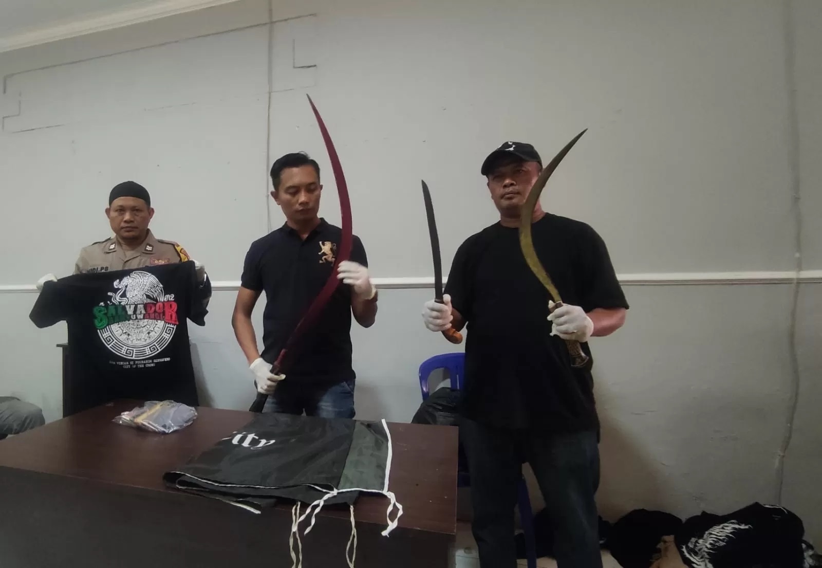 BUKTI: Kanit Reskrim Polsek Muncar Ipda Ocky Heru Prasetyo (tengah) bersama anggota menunjukkan celurit besar milik geng motor Salvador di Mapolsek Muncar Rabu (22/8) (Dedy)