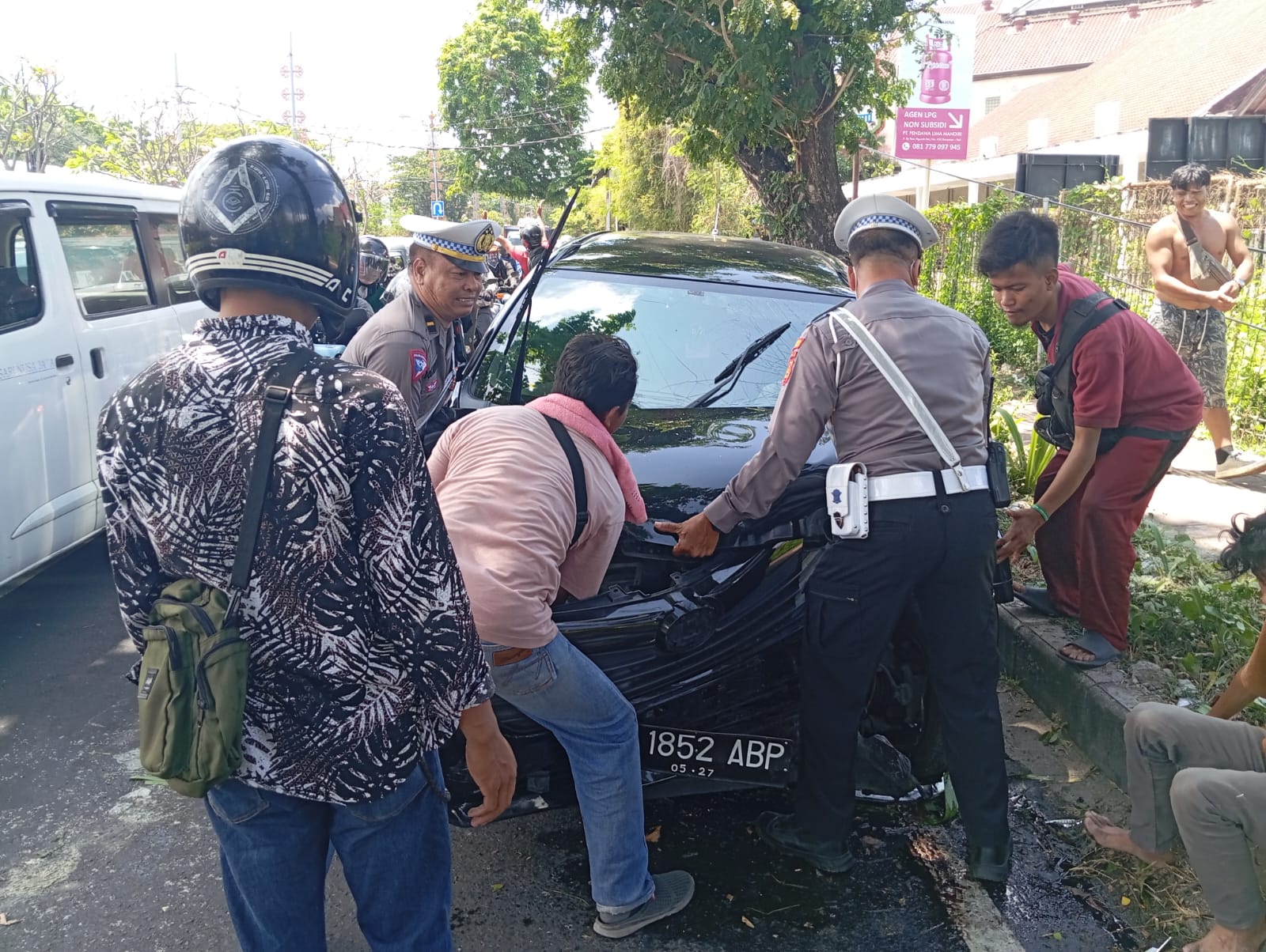 RINGSEK: Bagian depan mobil taksi online yang dikendarai Ferdi ringsek usai menabrak trotoar dan pohon di Bypass Ngurah Rai.