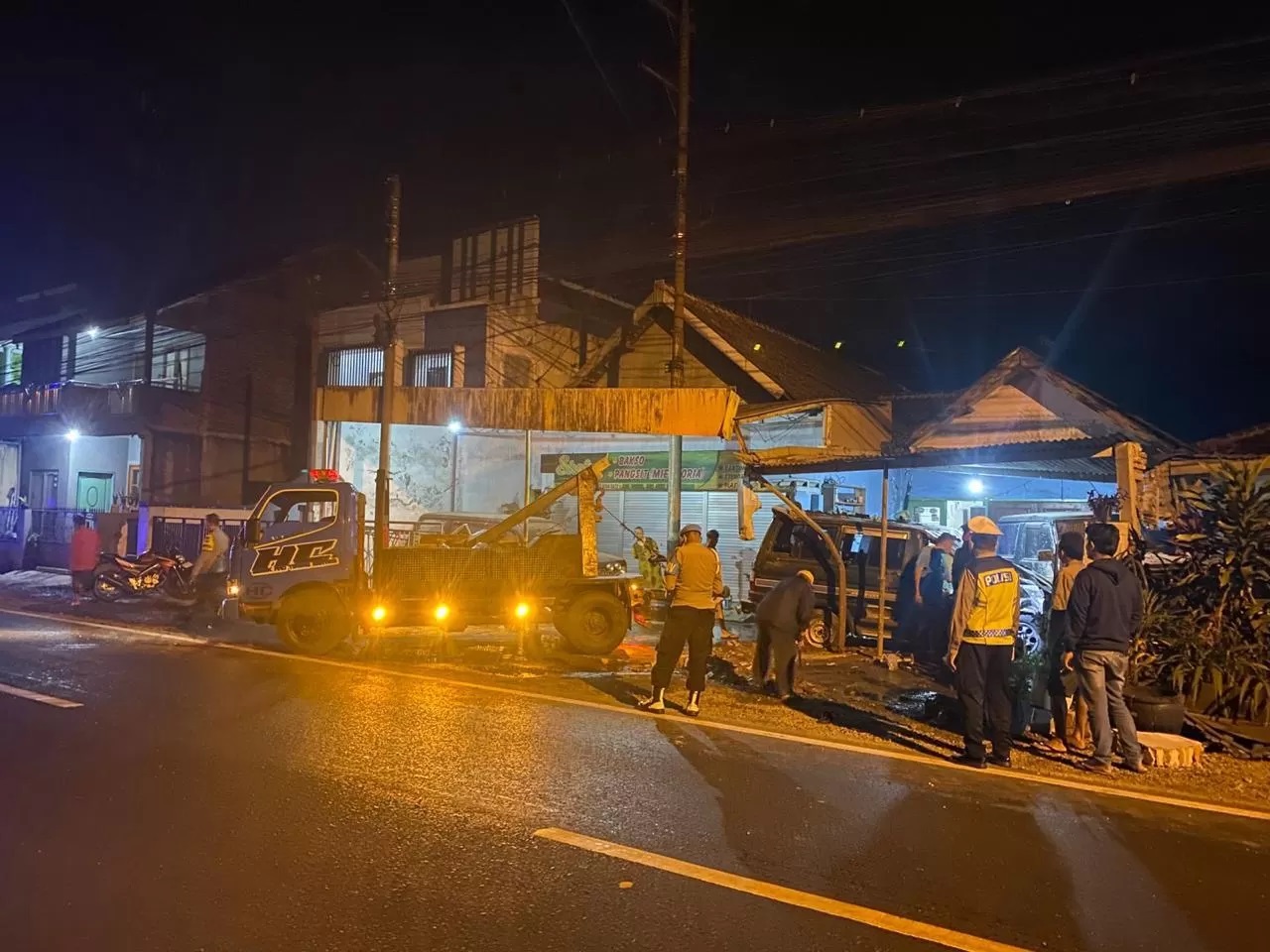 LAKA LANTAS: Mobil derek tiba di lokasi untuk mengevakuasi Toyota Kijang N 1831 FT yang ringsek akibat menabrak dua rumah warga Jalan Raya Genengan, Pakisaji, kemarin.