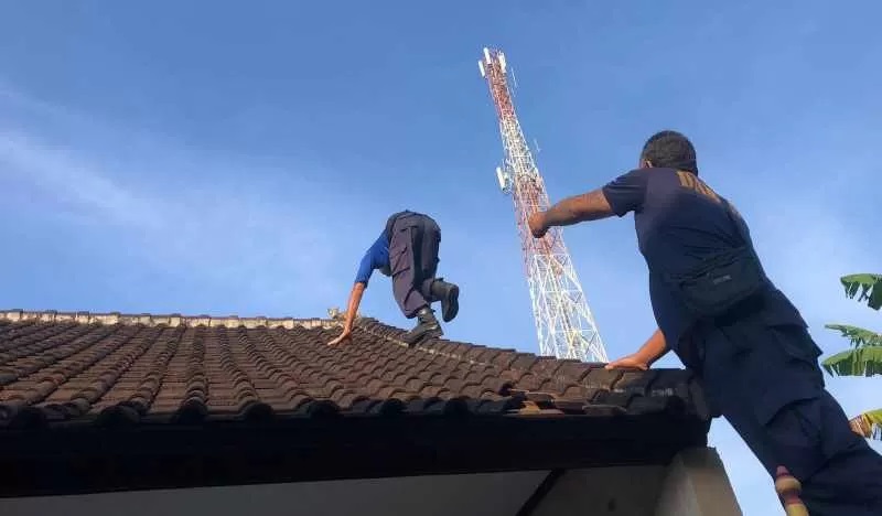 DEMI KUCING : Petugas Damkartan saat melakukan evakuasi seekor kucing yang tak bisa turun dari atap rumah di wilayah BTN Wahyu, Kelurahan Subagan. (Foto Dinas Damkartan Karangasem)