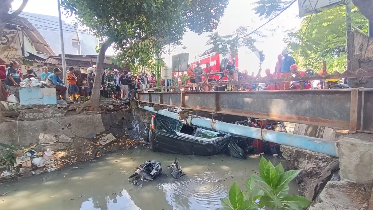 TERCEBUR : Mobil dan sepeda motor masuk sungai usai terlibat kecelakaan di Jalan Mulyorejo, Surabaya. (FOTO; ISTIMEWA/ RADAR SURABAYA)