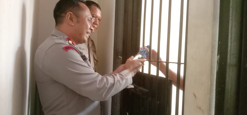 Petugas kepolisian saat memberikan air kepada pelaku kekerasan yang ditahan di Polsek Negara, Kecamatan Negara, Jembrana. (ISTIMEWA)
